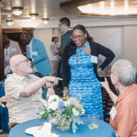 3 people point to woman while she is standing and smiling at them